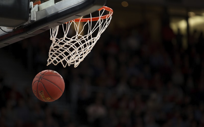 NBA篮球赛场上球员飞身扣篮的动感画面，观众席座无虚席